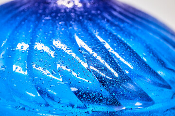 Naklejka na ściany i meble Cool water and water drops on a blue plastic bottle . Selective focus. Closeup