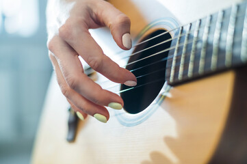 Close-up of female hands on an acoustic guitar. The girl learns to play the guitar