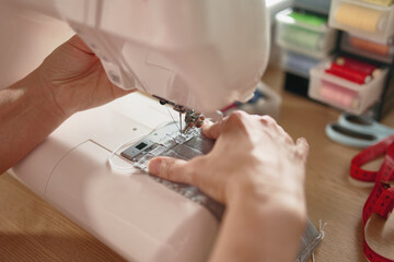 Obraz na płótnie Canvas Woman hands using the sewing machine to sew the face mask