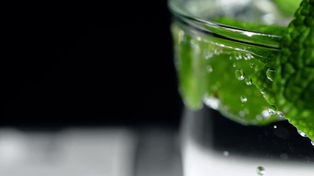 Macro close-up,refreshing soda tonic fizzy water, lime in Glass, ice. Slice of lemon, mineral bubbles. Detox or thirst concept. Healthy, dietary nutrition. Cold lemonade mojito drink. Black background