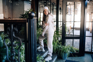 Woman stands on stairs of porch in front of the entrance to house.