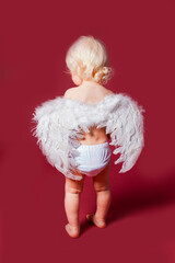 Toddler wearing angel white feather wings and stanc back.