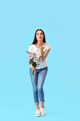 Beautiful woman with flowers blowing kiss on color background. International Women's Day celebration