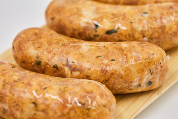 Raw sausages lie on a wooden Board, isolated on a white background. The concept of cooking food from semi-finished products. Italian traditions, Bavarian sausages