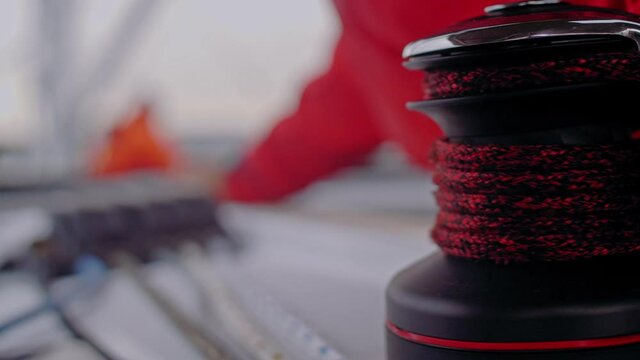Male yachtsman automatic winding rope closeup sailboat pulley or roller or cable winch yacht journey