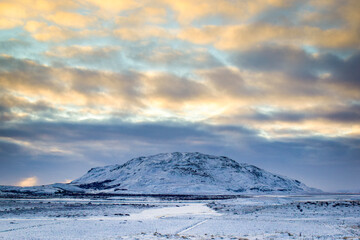 Fototapeta na wymiar solitary snowy mountain at the end of an icy plain. 