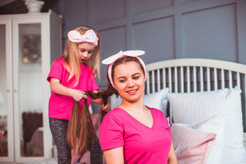 Little toddler girl combing her mother hair