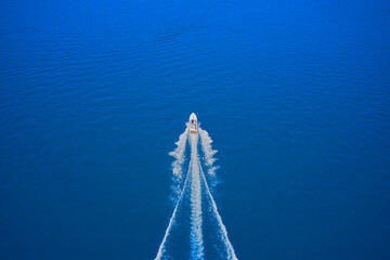 Top view of a white boat sailing in the blue sea. Drone view of a boat sailing at high speed....