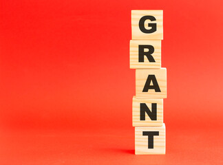 Wooden cubes with word GRANT. Wooden cubes on a red background. Free space on the left.