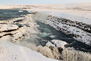 deep blue water, white foam and ice in a massive waterfall