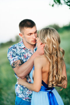 blonde girl with loose hair in a light blue dress and a guy in the light of sunset