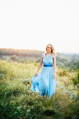 Obraz premium blonde girl with loose hair in a light blue dress and a guy in the light of sunset