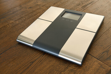 Bathroom scale for weight and body composition on dark hardwood floor