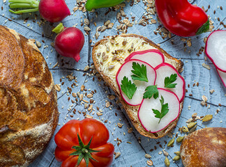 Slice of artisan bread with cream cheese, radish, butter decorated with parsley and seeds 