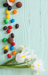Easter chocolate eggs and flowers on green wooden background