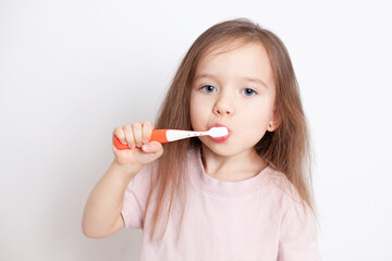 
Portrait of a girl of European appearance with light brown hair and blue eyes brushes her teeth. Hygiene. Dental care. Dentistry. Health.  