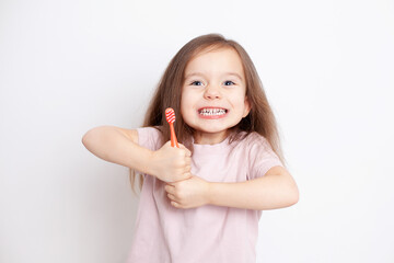 a little girl with fair hair and blue eyes with a toothbrush in her hands smiles very broadly. Dental health. Dentistry. Oral cavity care. Hygiene. Pampering. Emotions. Portrait in neutral colors