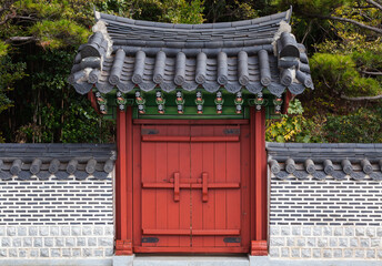 Red wooden gate under tiled roof. Oriental park