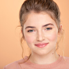 Fototapeta premium Closeup portrait of an young girl over colored background. Photo of a fashion model posing at studio. Pretty young woman with brown hair looking at camera. Beauty portrait.