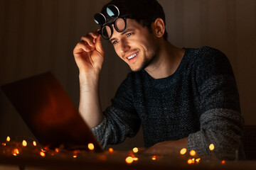 Night portrait of young man working at laptop home.