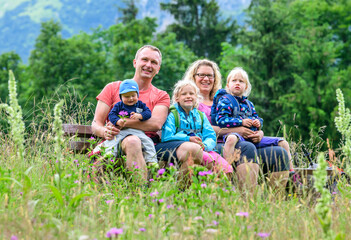 Naklejka na ściany i meble Junge Familie auf einer Bank inmitten einer Kräuterwiese im Allgäu sitzend