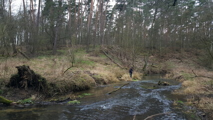 Silhouette of a fisherman, a rod and a breathtaking scene in the winter forest with beautiful reflections on the river. Article about fishing day hunting for a trout.