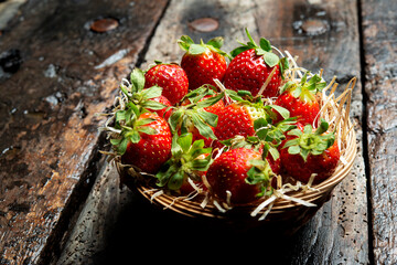 red Strawberries in a basket on old dark wooden table
