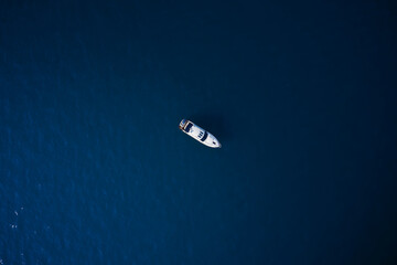 Fototapeta na wymiar Drone view of a boat across the blue clear waters. Aerial view of luxury ship at sunset, blue sea. Yacht at the sea in Europe. Top view from drone of yacht. High altitude air view
