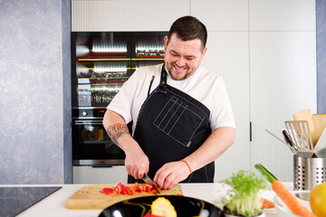 40 years man chef cooker in a white uniform and a black apron in the kitchen of the restaurant...