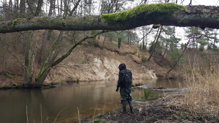 Silhouette of a fisherman, a rod and a breathtaking scene in the forest with colourful reflections on the river. Article about fishing day hunting for a trout.