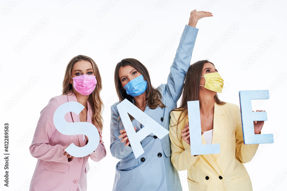 Poster Three women in pastel suits holding sale letters over white background