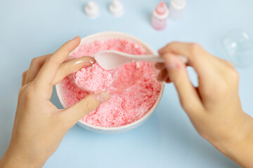 a child makes a bath bomb from sea salt, citric acid, soda, dye and flavor on a blue background,...