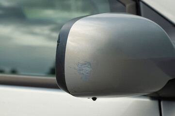The consequences of a small car accident. Side rearview mirror with scratches and chipped close-up. Repairs are required at the service station. Insurance against accidents.