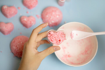 a child makes a bath bomb from sea salt, citric acid, soda, dye and flavor on a blue background,...