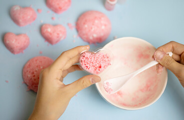 a child makes a bath bomb from sea salt, citric acid, soda, dye and flavor on a blue background,...