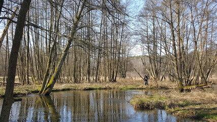 Silhouette of a fisherman, a rod and a breathtaking scene in the forest with colourful reflections on the river. Article about fishing day hunting for a trout.