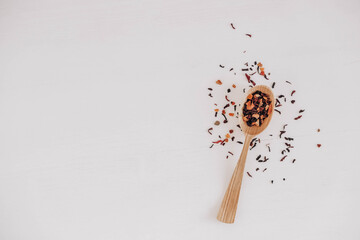 Dry fruit tea in a wooden spoon scattered on a white background. Top view. Copy, empty space for...
