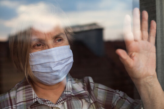 Portrait Of Elderly Senior Citizen Wearing Face Mask Looking Through Room Window