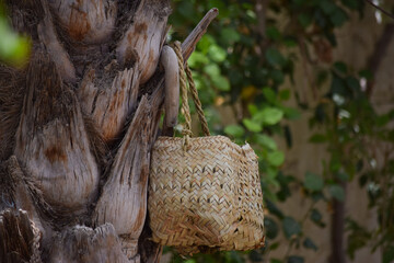 Human hand made dates tree box tool. palm leaf dry jar hanging on wood in garden, brown background culture thing Arabic style picture