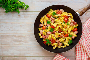 Durum wheat semolina pasta with tomato, green peas in pan.
