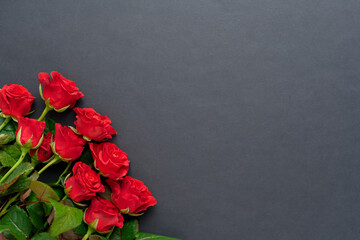 A bouquet of red roses with a beautiful ribbon on a black background, copyspase.