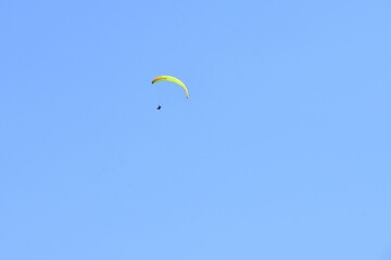Paragliding in blue sky, soft focus, copy space. Paraglider flying in bright sunny day. 