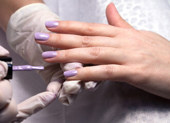 The process of manicure fitting natural nails filing nails coating with colored gel polish and glossy top.