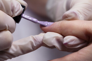 The process of manicure fitting natural nails filing nails coating with colored gel polish and glossy top.