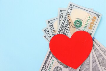 Red heart and Dollars banknotes on blue background. Business and love concept.
