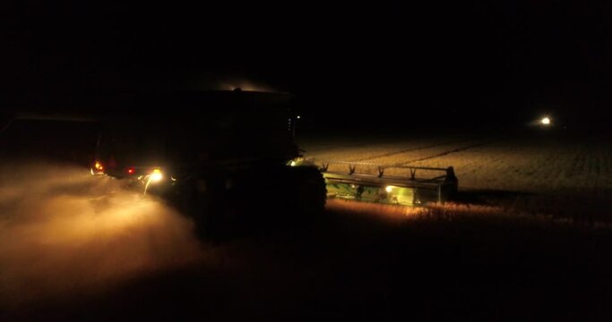 Tractor harvesters working at night countryside corn fields drone aerial view 4K 