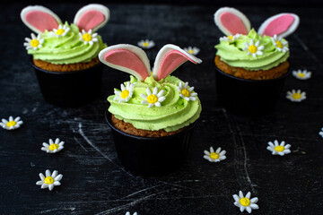 Easter cupcake with whipped green cream. Bunny ears stick out and daisies. low key