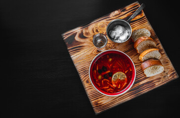 Solyanka soup with meat, sausage, vegetables, olives and lemon in bowl on black wooden table...