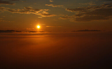 Fototapeta na wymiar Sun rising above fog covered landscape in early summer morning