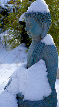 A blue colored buddha statue covered by snow.